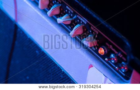 Musician turning the volume on amp up to make the music louder