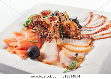 Fish platter with pink salmon, grilled eel, oil fish balyk and red caviar on elegant restaurant plate isolated on white background. Exquisite serving thin slices of salted and dried delicious seafood