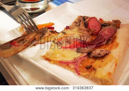 Eating Of Pizza Slice With Knife And Folk. Close Up Of White Plate On Table In Pizzeria. The Nicetie