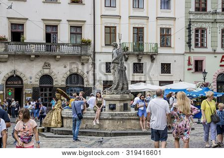 Lviv, Ukraine - August 13, 2019: People Have A Rest Near The Neptune Fountain On Rynok Square In The