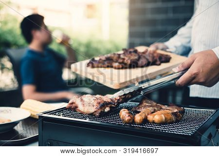 Close Up Asian Hand Man Are Pinching The Pork On The Grill And Holding It To Friends Who Are Celebra