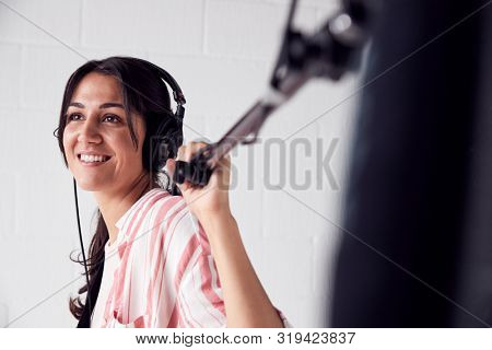 Female Sound Recordist Holding Microphone On Video Film Production In White Studio