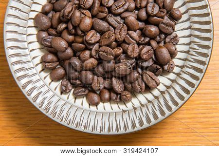 Coffee Beans On A Plate Placed On A Wooden Table.