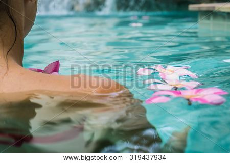 Woman In A Swimming Pool. Tropical Flowers Frangipani Plumeria, Leelawadee Floating In The Water. Sp