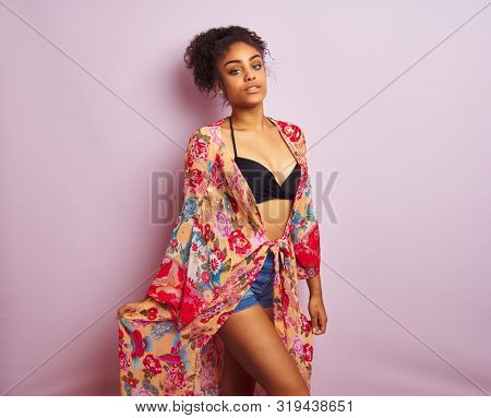 Young beautiful african american woman on vacation standing wearing bikini and colorful caftan