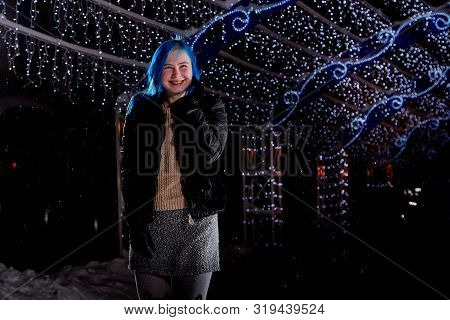 Girl With Blut Hair Skating On The Ice Arena In The Evening City Square In Winter