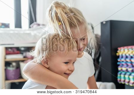 Cute Adorable Blond Caucaian Little Sister Hugging Her Toddler Brother.couple Of Cheerful Sibling Pl