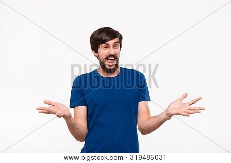Good Looking Brunet Man In A Blue Shirt With Beard And Mostaches Shrugging His Shoulders Being Surpr