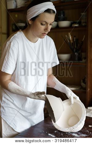 Beautiful Young Woman Takes Out A Clay Bowl From A Mold