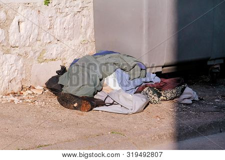 Overfilled Trash Dumpster Near Street. Old Clothes And Shoes Waste Left Near To Trash Dumpsters On T