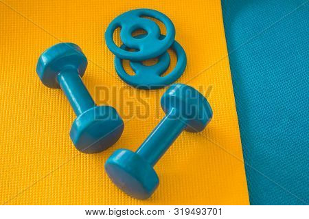 Water, Sports Blue Dumbbells At Karemat In The Gym. Sport Accessories. Sport Equipment Top View Back