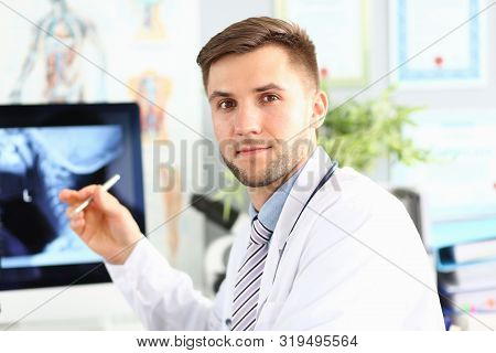 Portrait Of Physician Posing In Clinic Office. Smart Doctor Showing Picture Of Body On Laptop. Medic
