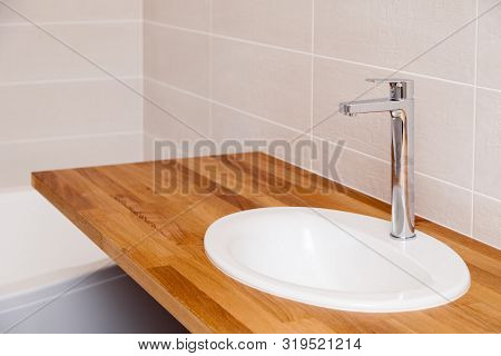 Closeup Brown Teak Wooden Empty Tabletop With White Round Ceramic Sink And Tall Silver Water Faucet.