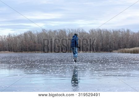 Skating On The Lake. Man Ice Skating Outdoors On A Pond Or River. Rear View.