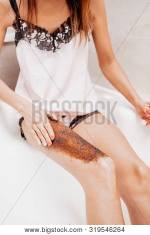 Slim Young Woman In A Bright Silk Pajamas Scrabs Her Leg Sitting In A Big Beautiful Bright Bath. Ski