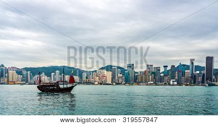 Chinese Traditional Junk Boat In Front Of Hong Kong Island City Skyline With High Skyscrapers, Panor