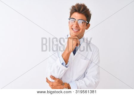 Young handsome sciencist man wearing glasses and coat over isolated white background looking confident at the camera smiling with crossed arms and hand raised on chin. Thinking positive.