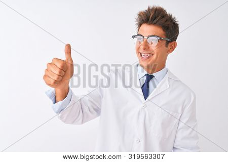 Young handsome sciencist man wearing glasses and coat over isolated white background Looking proud, smiling doing thumbs up gesture to the side
