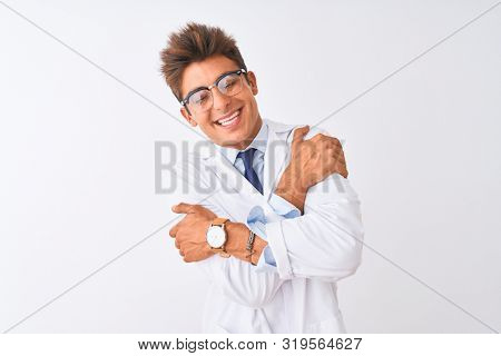 Young handsome sciencist man wearing glasses and coat over isolated white background Hugging oneself happy and positive, smiling confident. Self love and self care
