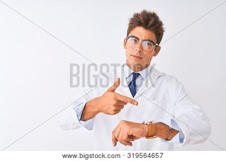 Young handsome sciencist man wearing glasses and coat over isolated white background In hurry pointing to watch time, impatience, upset and angry for deadline delay