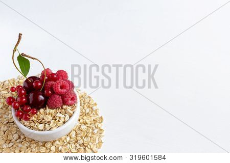 Oatmeal With Cherries, Raspberries And Red Currants In A Cup Against A White Background.