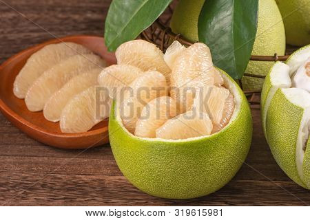 Fresh Peeled Pomelo, Grapefruit, Shaddock With Green Leaves On Dark Wooden Plank Table. Seasonal Fru