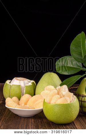 Fresh Peeled Pomelo, Grapefruit, Shaddock With Green Leaves On Dark Wooden Plank Table. Seasonal Fru