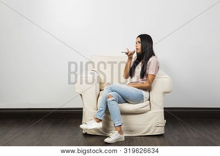 Young Woman, Sitting On A White Couch, Talking On Her Phone