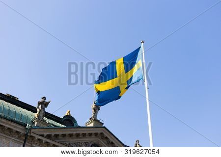 Flag Of Of Sweden Against House Of Nobility Riddarhuset And Blue Sky Background