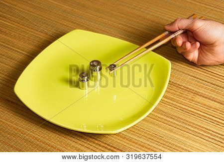 Metallic Weight And Sushi Chopstic On A Dish