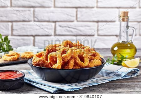 Crispy Calamari Rings, Deep-fried Breaded Squid Rings Served With Tomato Sauce In A Black Bowl On An