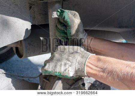 Hands In Defense Gloves Mechanics To Repair The Suspension On The Car. Work With A Wrench. Self-repa