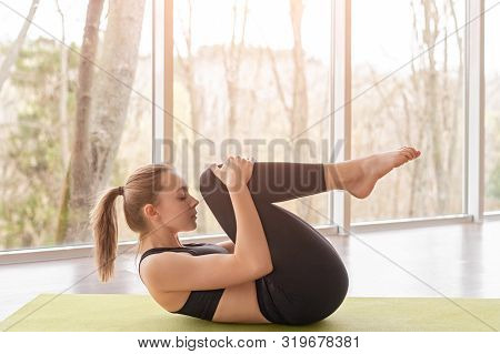 Side View Of Meditative Woman Practicing Wind Removing Position While Strengthening Back Muscles