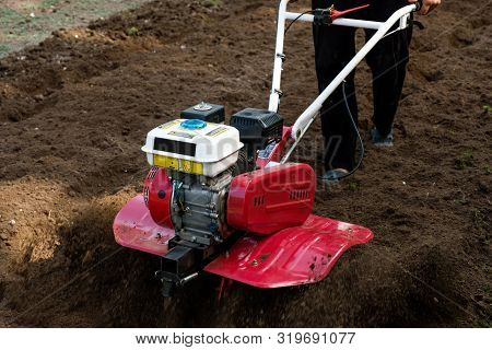 Man Working In The Garden With Garden Tiller Machine. Garden Tiller To Work, Close Up
