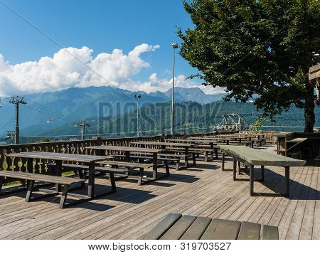 Wooden Benches And Tables Against The Backdrop Of Beautiful Mountains At Rosa Khutor