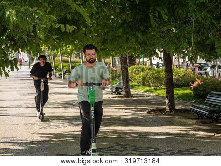Lisbon, Portugal - 9 August 2019: People Riding A Lime S Electric Scooter Along Avenida Da Liberdade