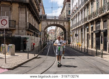 Lisbon, Portugal - 9 August 2019: Man Riding A Lime S Electric Scooter Along Narrow Streets Of Lisbo
