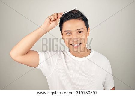 Portrait Of Smiling Man In T-shrit Combing His Hair.