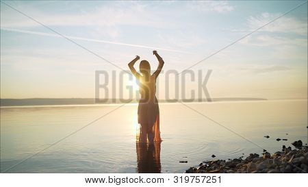 Girl In A Light Dress On The Beach At Sunrise. Beautiful Women In A Light Pink Dress Walking Along T