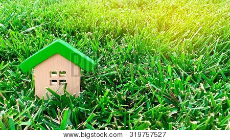 Miniature Wooden House On Grass. Real Estate Concept. Eco-friendly And Energy Efficient House. Buyin