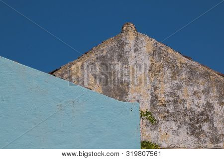Wall Of An Old House, Creating A Tringle With The Roof Line. Weathered Facade, Blue Wall Of A House 