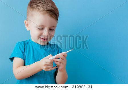Ill Young Child With A Thermomether, Measuring The Height Of His Fever And Looking Into The Camera