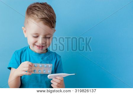 Ill Young Child With A Thermomether, Measuring The Height Of His Fever And Looking Into The Camera