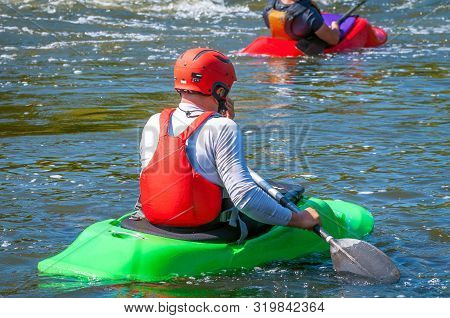 Playboating. A Man Sitting In A Kayak With Oars In His Hands Performs Exercises On The Water. Kayaki
