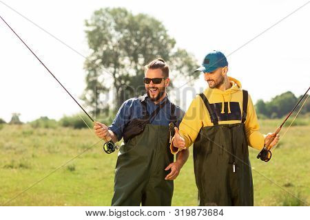 Two Fishermen Preparing For Fishing. They Hold The Fishing Rods And Talk To Each Other. Sport Fishin