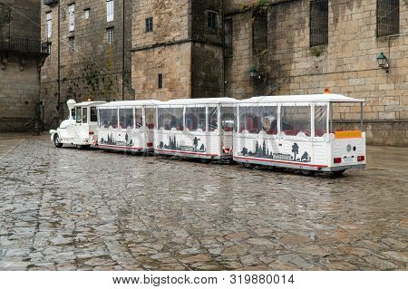 Tourist Road Train On Obradoiro Square On A Rainy Day. Santiago De Compostela Tourism
