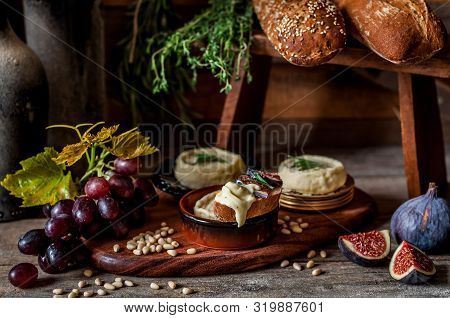Soft Spreadable French Stinky Cheese On A Slice Of Bread With Fruit And Pine Nuts
