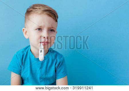 Ill Young Child With A Thermomether, Measuring The Height Of His Fever And Looking Into The Camera