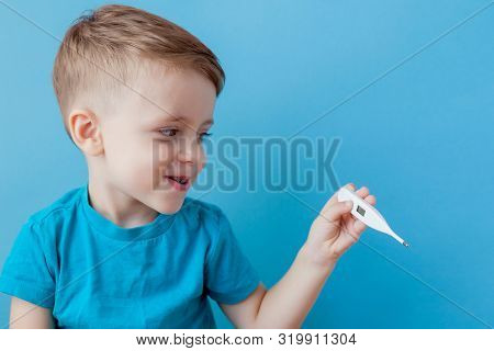 Ill Young Child With A Thermomether, Measuring The Height Of His Fever And Looking Into The Camera