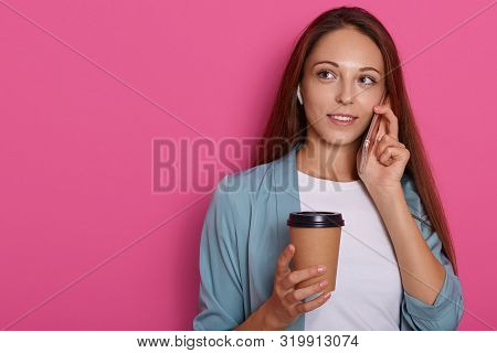 Studio Photo Of Beautiful Girl Isolated Over Rose Background, Holding Takeaway Coffee Cup While Talk